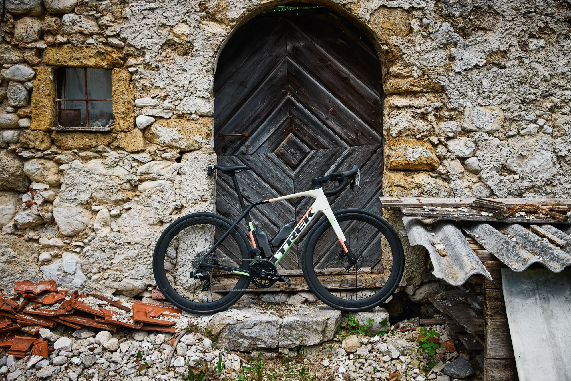 Trek Domane 5ª geração encostada em uma construção de pedra, mostrando o quadro em carbono e o design mais limpo da nova bicicleta de estrada